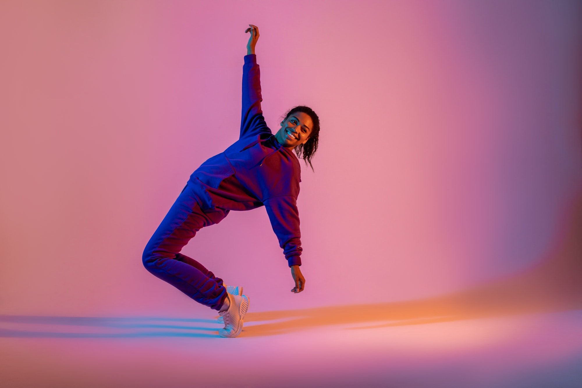 Dancing as hobby. African american female hip-hop dancer expressing emotions in dancing, pink neon
